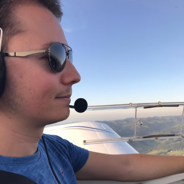 Junger Mann mit Sonnenbrille in Flugzeug.
