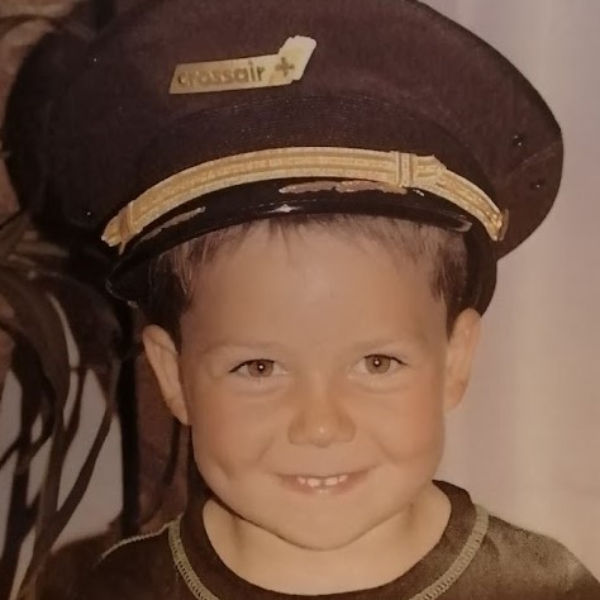 Kleiner Junge mit einer Piloten-Mütze lacht.