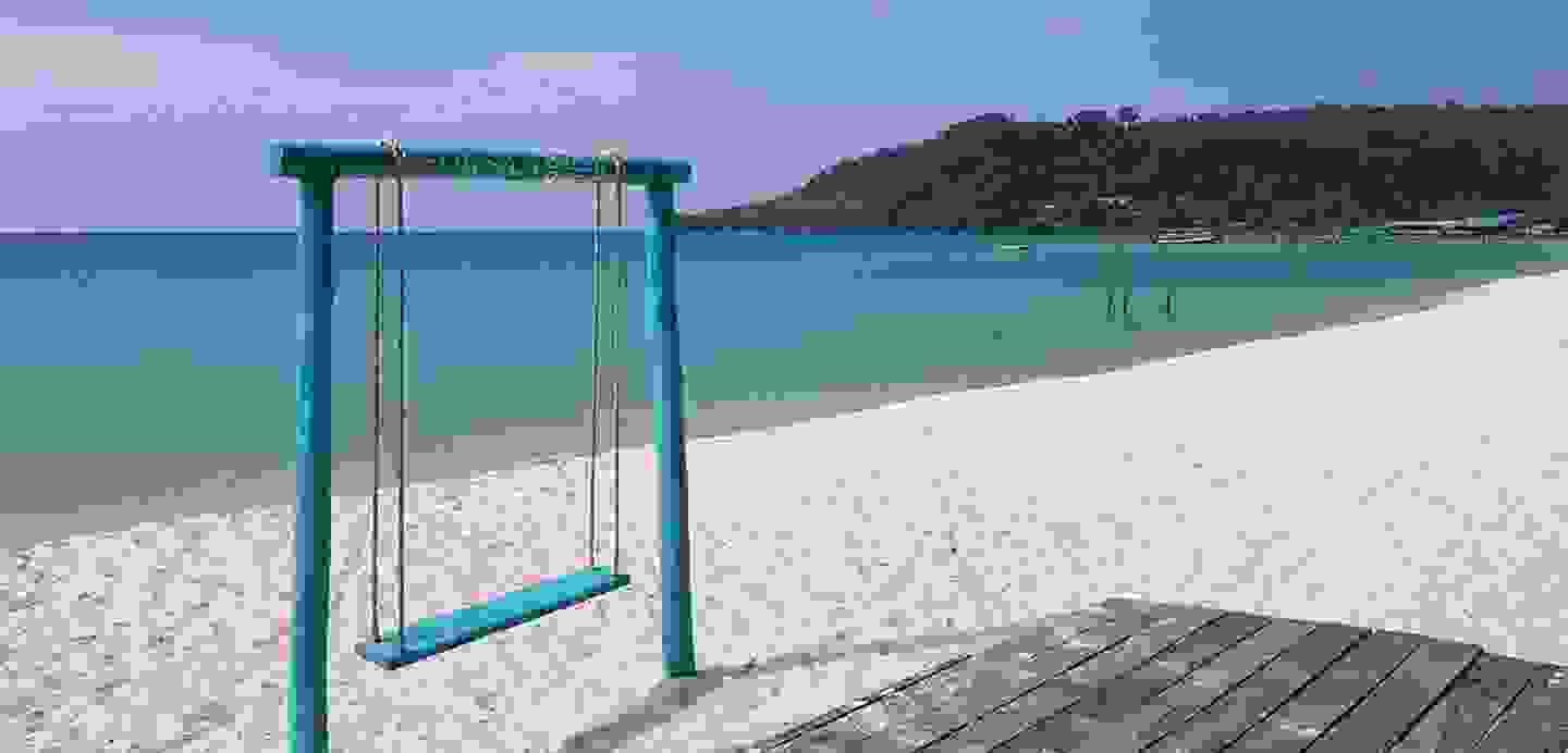Stimmungsbild mit Strand, Meer und Schaukel.