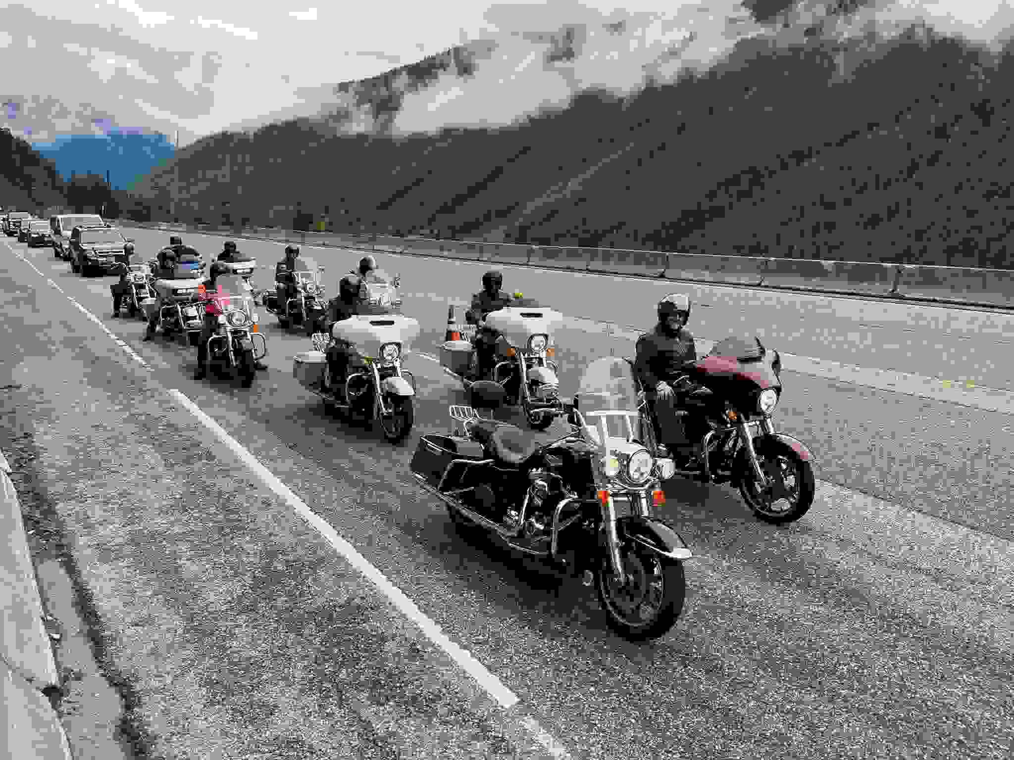Mehrere Motorräder warten hintereinander auf einer Autobahn.