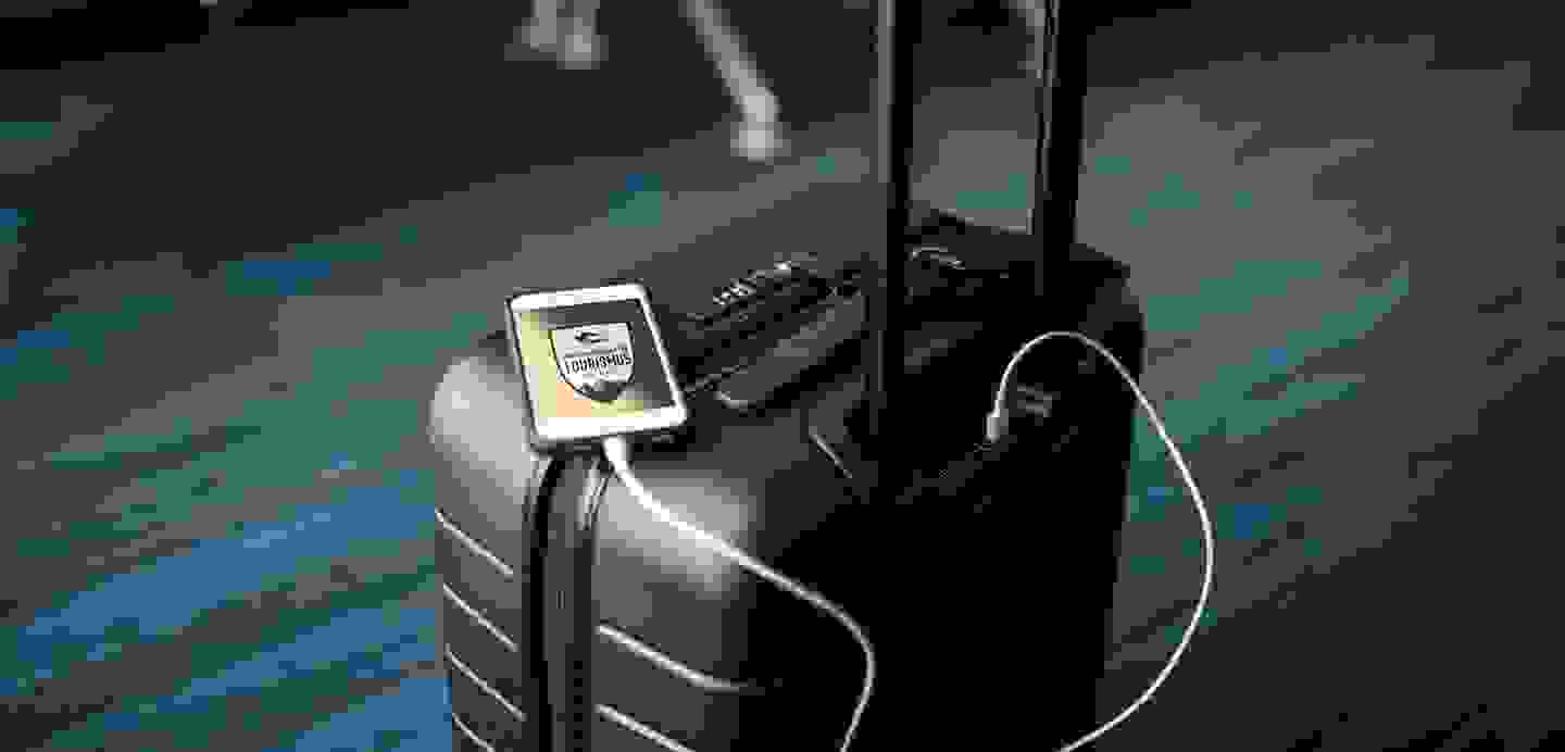 Stimmungsbild mit Reisekoffer und Handy inklusive TFBO-Aufkleber.