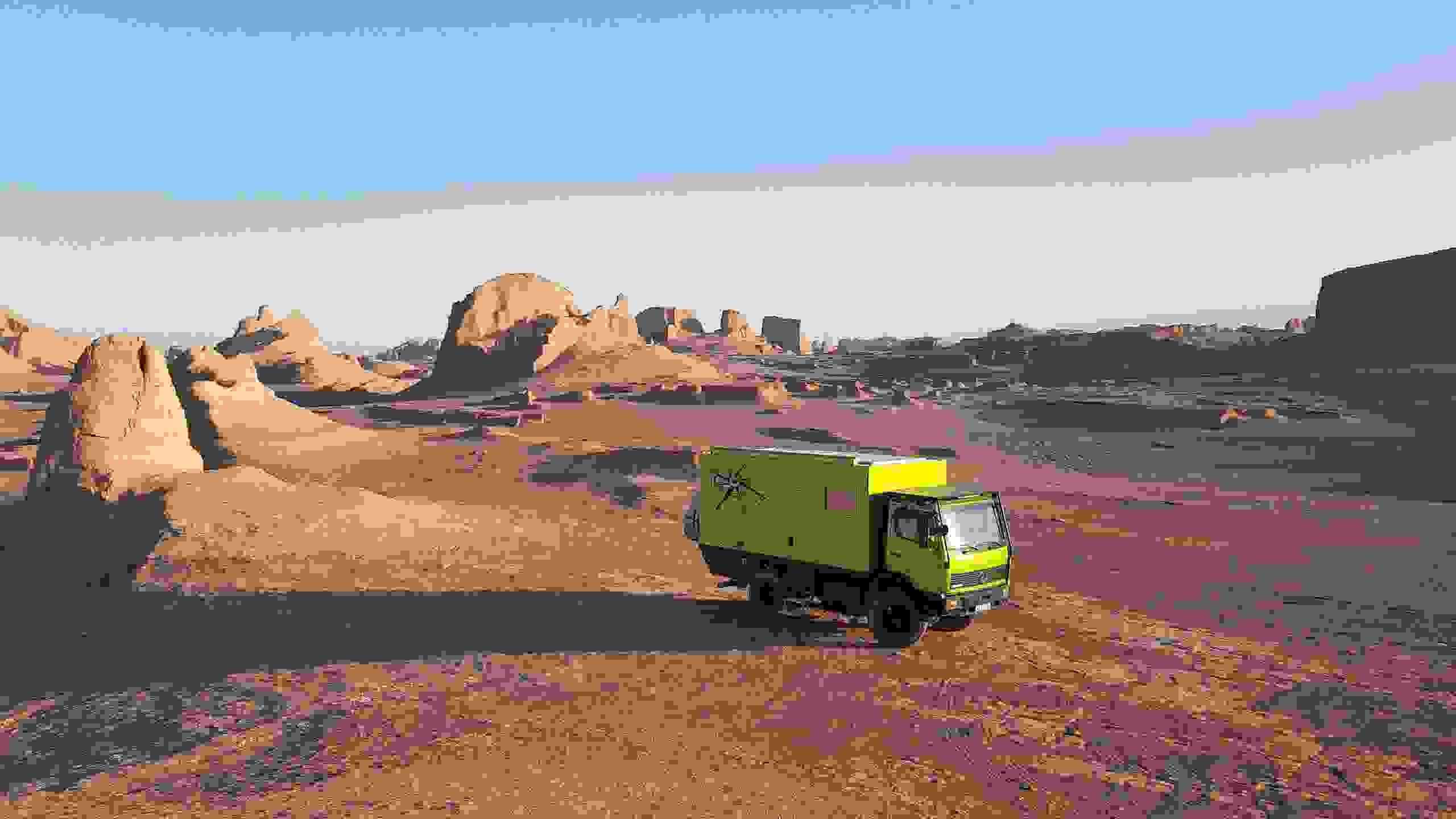 Grosses grünes Fahrzeug fährt durch Wüste.