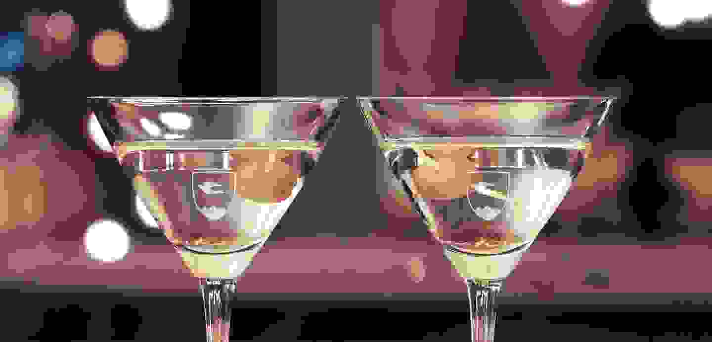 Stimmungsbild: Zwei Gläser gefüllt mit einem Getränk und einer Olive stossen gemeinsam an Auf den Gläsern ist das TFBO-Logo zu sehen.